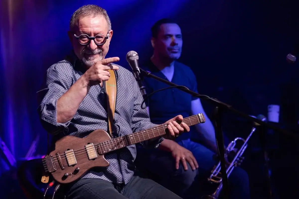 Musician playing a Laika travel guitar on stage