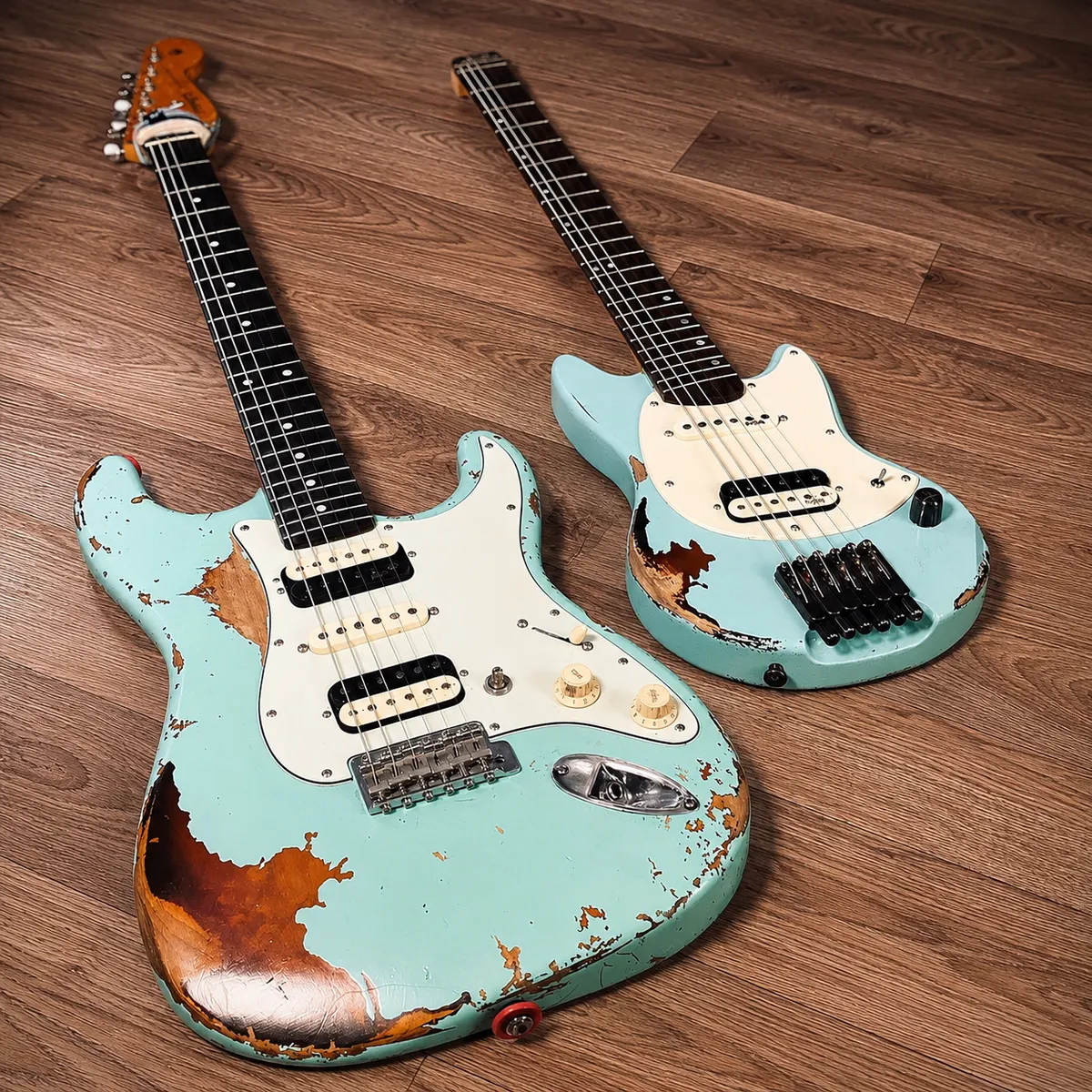 Two Laika travel guitars side by side on a wooden floor
