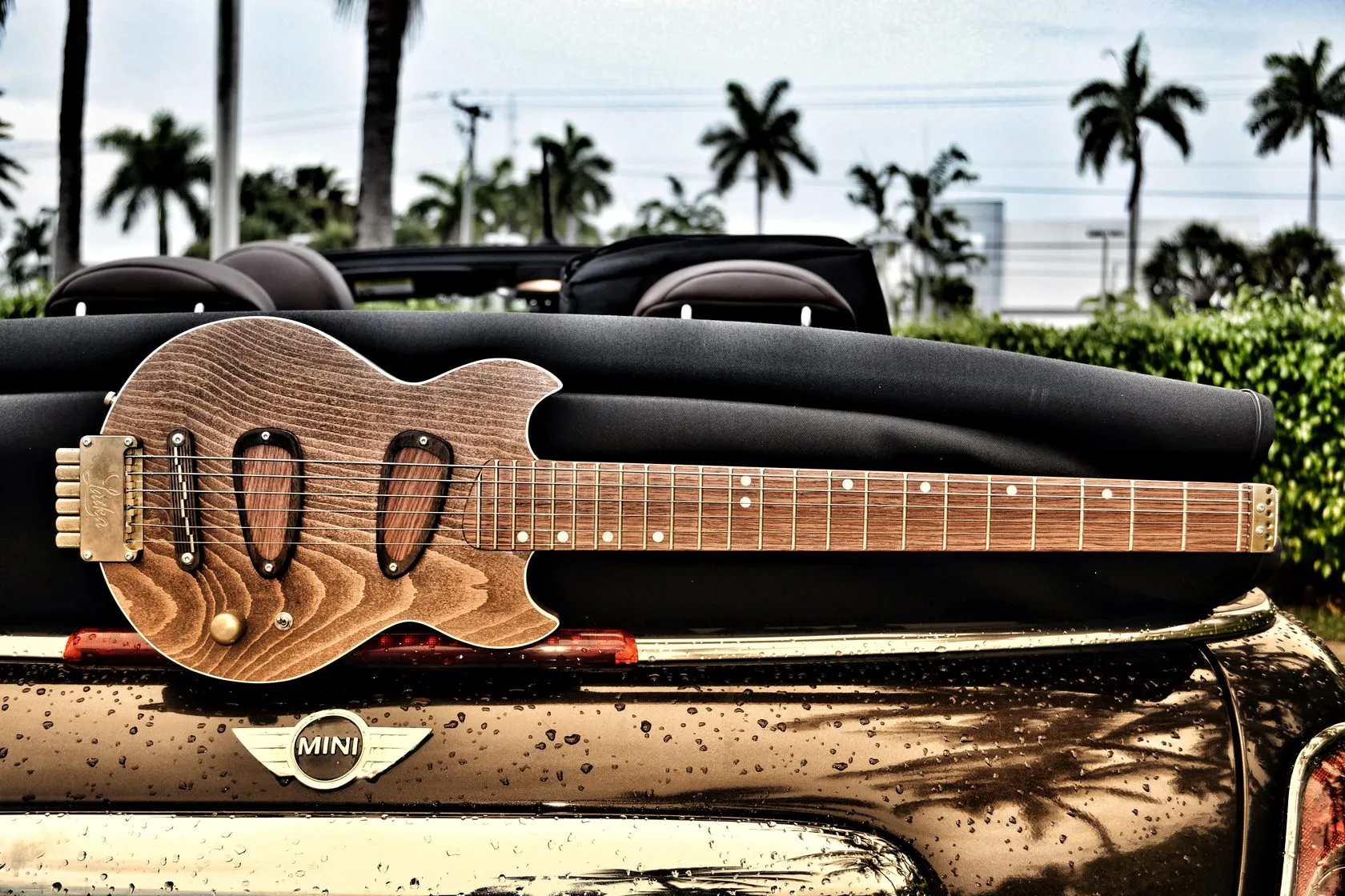 Laika travel guitar on the trunk of a MINI convertible under palm trees